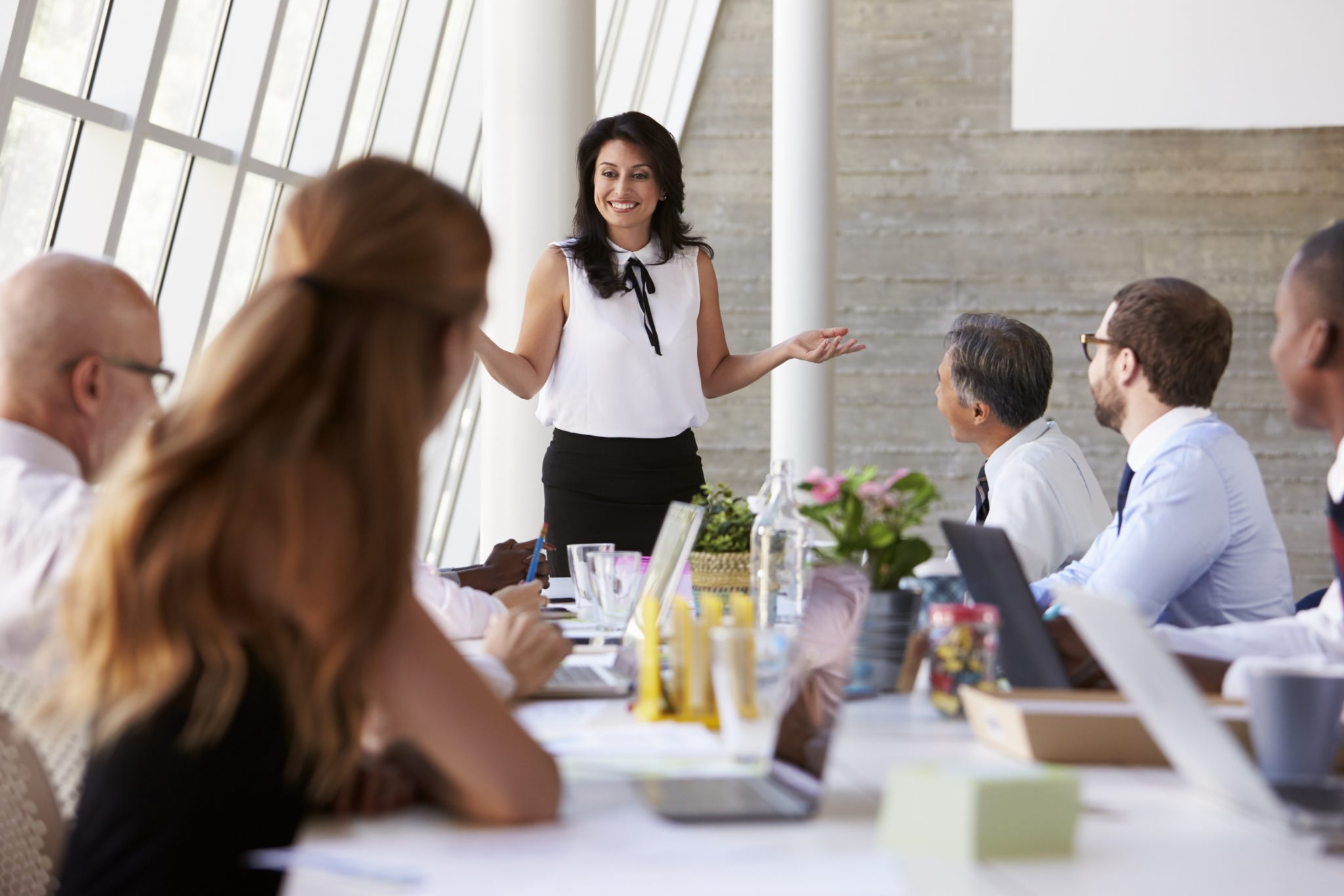 Hispanic Businesswoman Leading Meeting At Boardroom Table